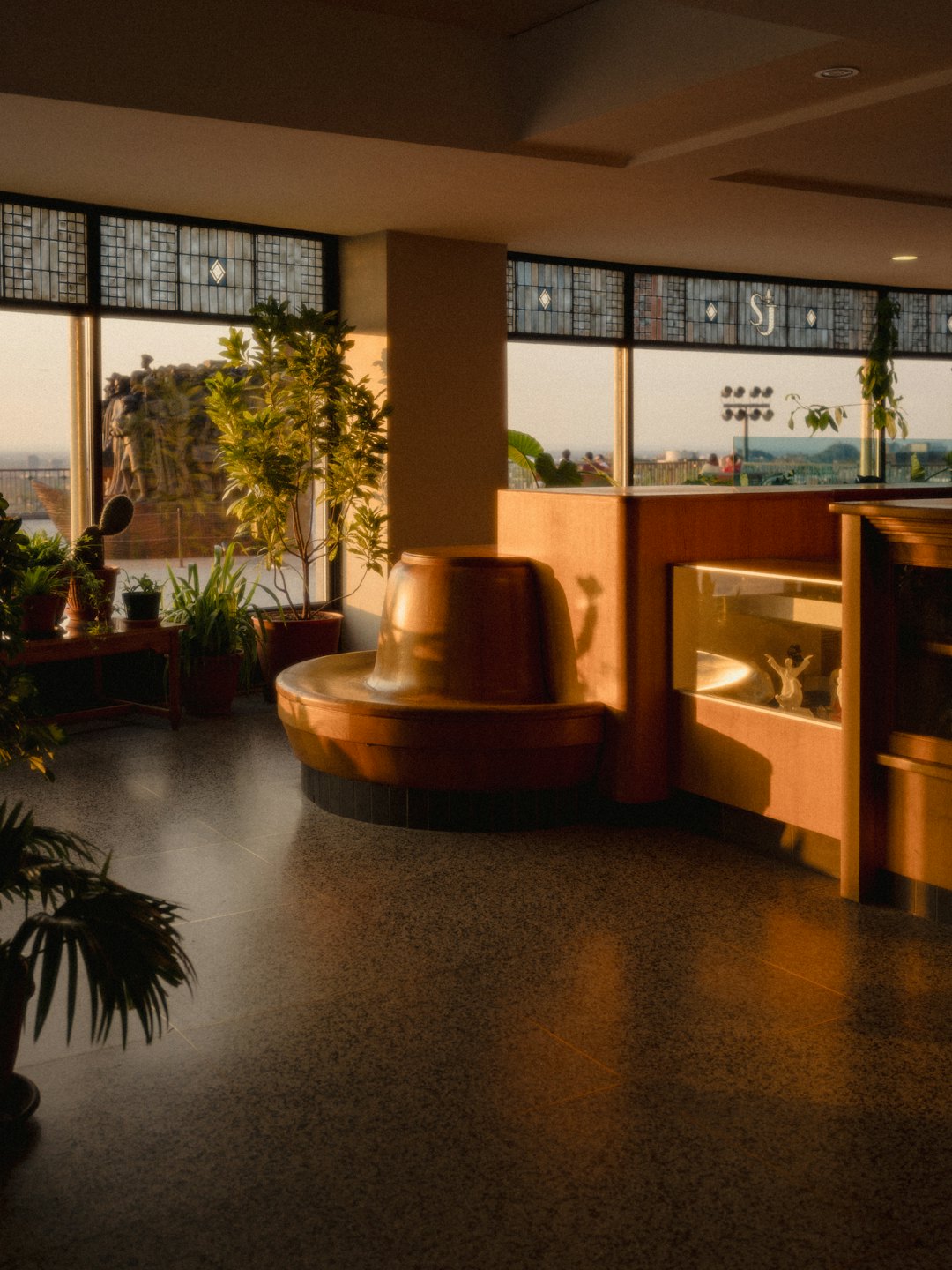 Interior lounge with large windows and potted plants.